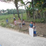 Kids along the road with help signs